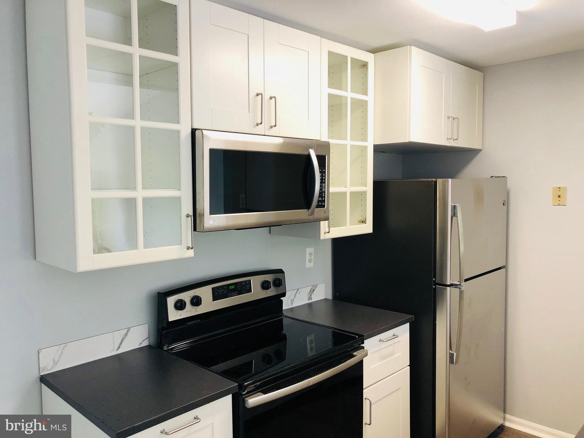 11510 Little Patuxent Parkway, Unit 407 Columbia, MD 21044 - Photo 11 of 15 a kitchen with stainless steel appliances a refrigerator a stove a microwave and cabinets