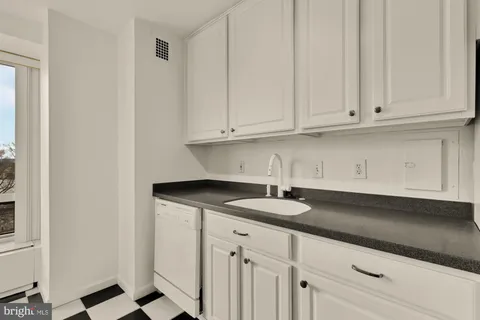 a kitchen with granite countertop white cabinets and sink