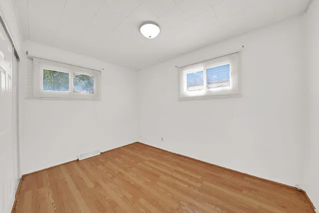 a view of a big room with wooden floor and windows