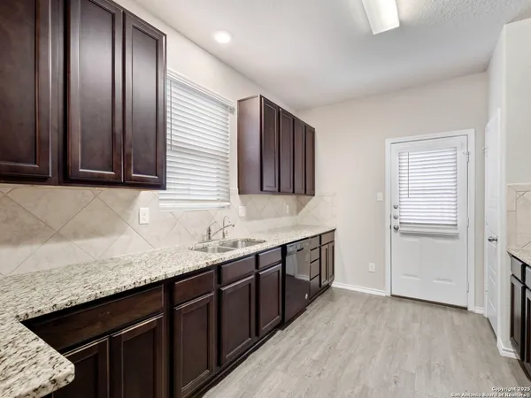 a kitchen with granite countertop stainless steel appliances a sink stove and cabinets