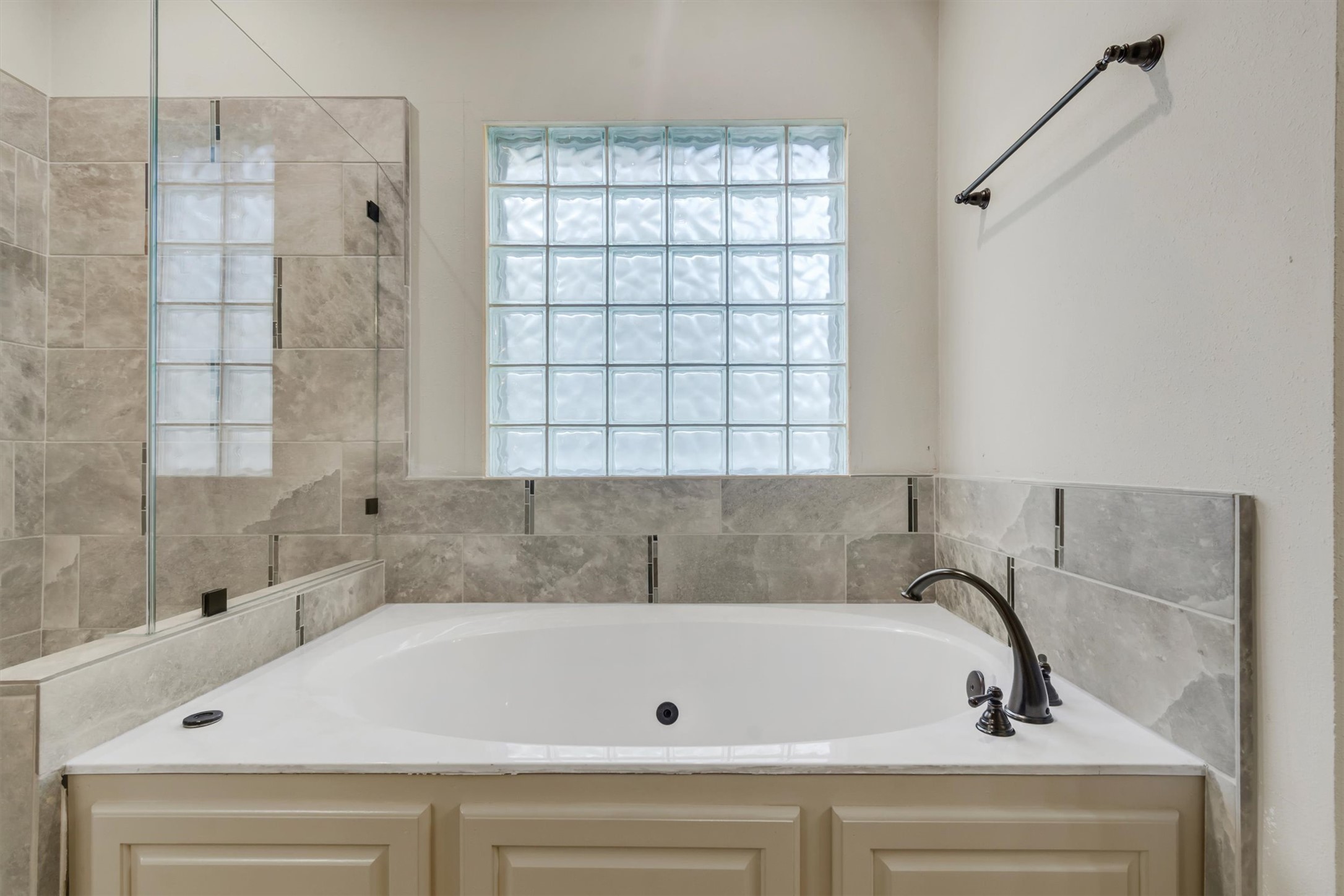 6008 Tributary Ridge Court Austin, TX 78759 - Photo 16 of 36 A deep soaking tub with surrounding tile and a privacy glass block window offers a serene bathing experience.