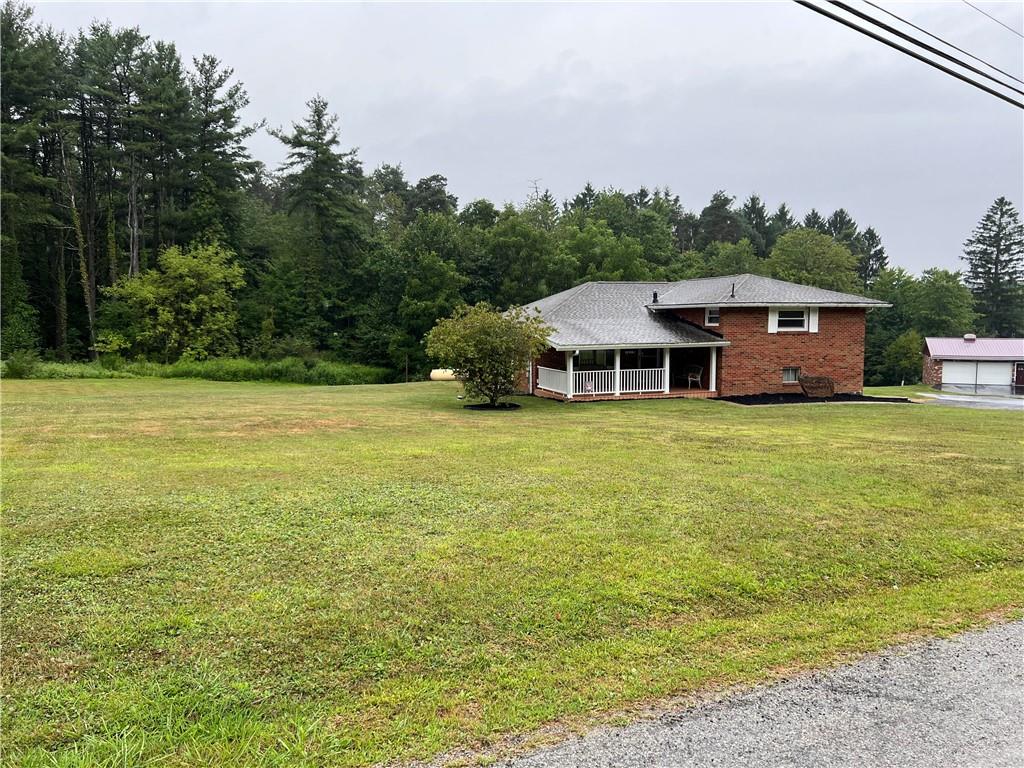 a view of a house with yard and trees in the background