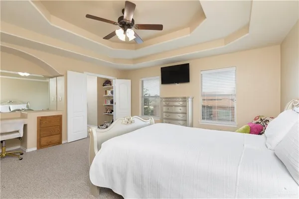a bedroom with a large bed a flat tv screen and a dresser