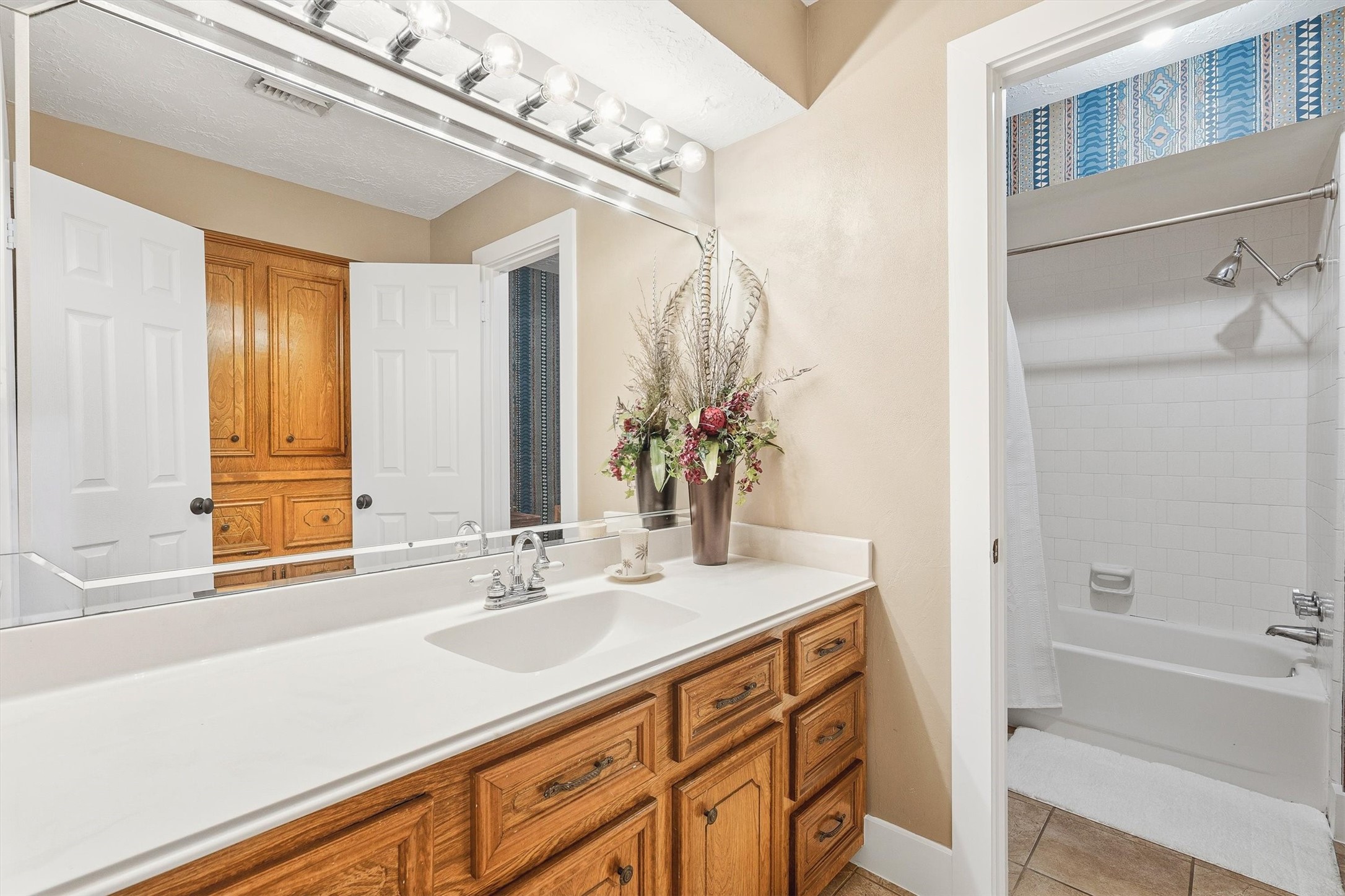 826 North Rivershire Drive Conroe, TX 77304 - Photo 28 of 46 The secondary bath serves the guest bedrooms with a wide single vanity, cultured marble countertop, wood cabinetry, and a well lit mirror that makes the space feel open and functional.