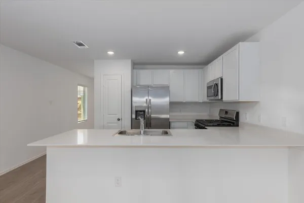 a kitchen with stainless steel appliances a sink a stove a microwave a sink a refrigerator and cabinets