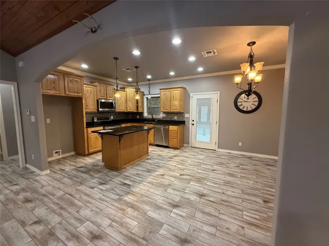 a kitchen with stainless steel appliances kitchen island granite countertop a stove and a wooden floors
