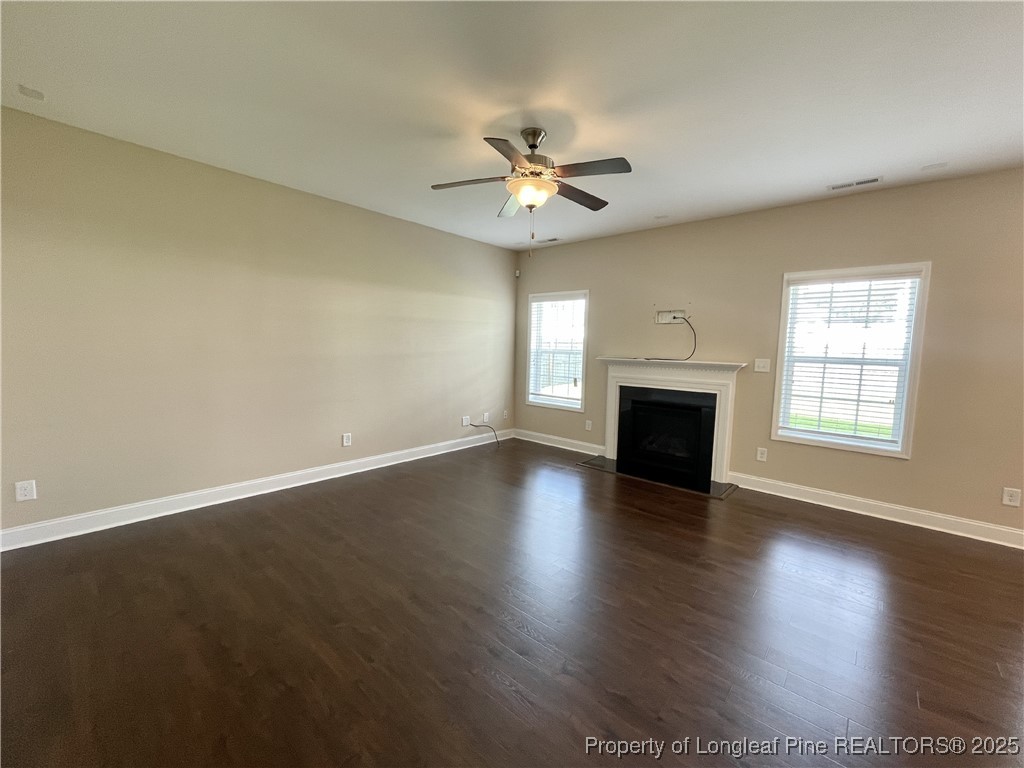 608 Stonebriar Avenue Raeford, NC 28376 - Photo 20 of 29 an empty room with wooden floor a ceiling fan a fireplace and windows