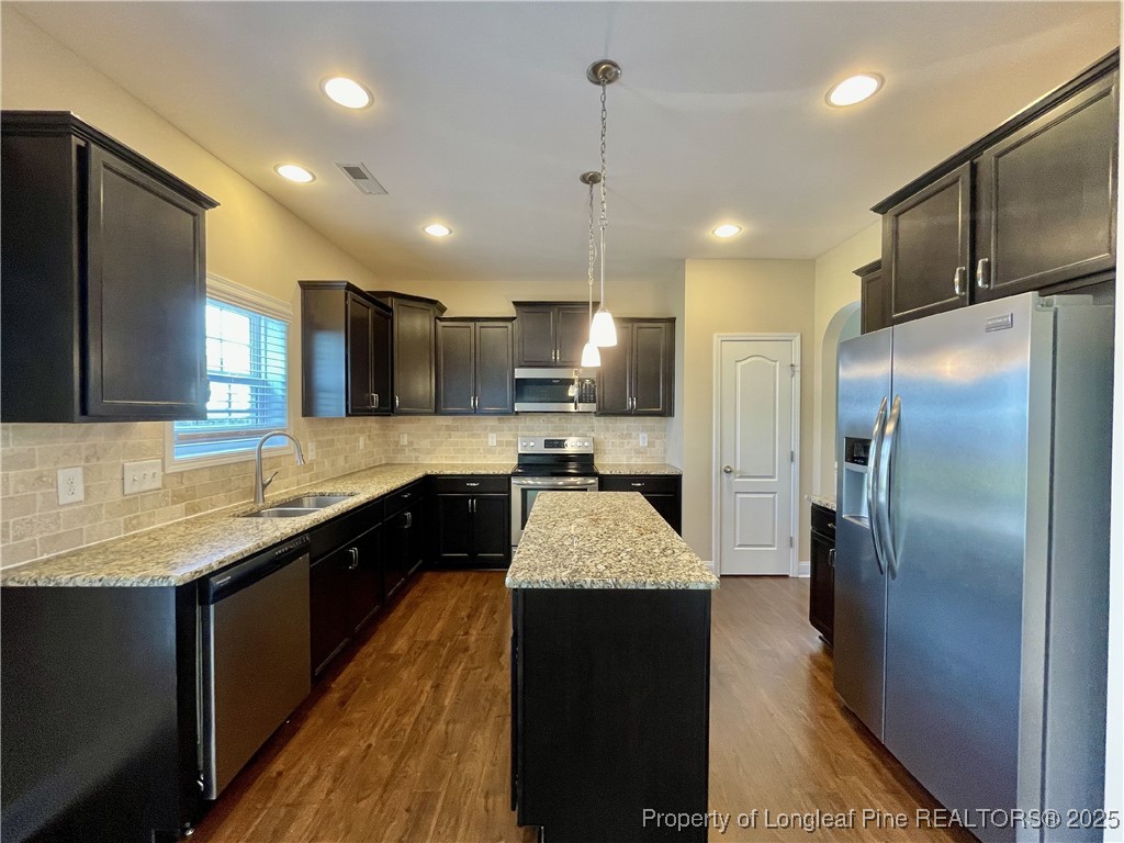 608 Stonebriar Avenue Raeford, NC 28376 - Photo 23 of 29 a large kitchen with stainless steel appliances kitchen island granite countertop a refrigerator a sink dishwasher a stove and a large countertops with wooden floor