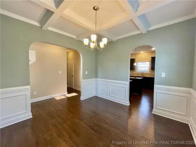 a view of a room with wooden floor chandelier and windows