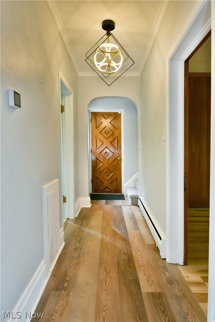 892 Yankee Run Road Masury, OH 44438 - Photo 23 of 50 Hallway featuring wood-finish flooring, white crown molding, a decorative ceiling light fixture, and a paneled wooden door