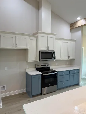 a view of kitchen with stainless steel appliances refrigerator stove and wooden floor
