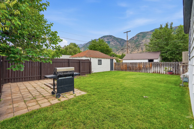 707 East 150 South Provo, UT 84606 - Photo 28 of 31 Expansive backyard featuring a lush lawn, a paved patio area, and a privacy fence