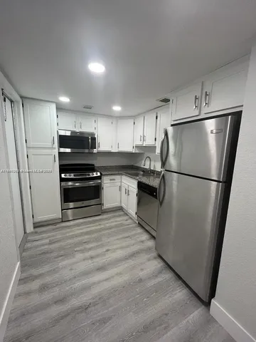 a view of kitchen with stainless steel appliances refrigerator stove microwave and cabinets