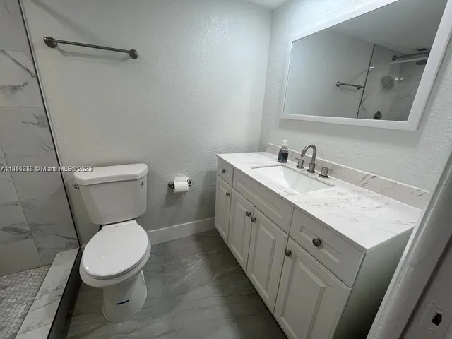 a bathroom with a granite countertop toilet sink and mirror