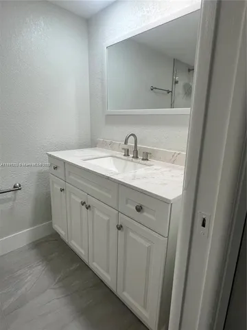 a spacious bathroom with a granite countertop sink and a mirror