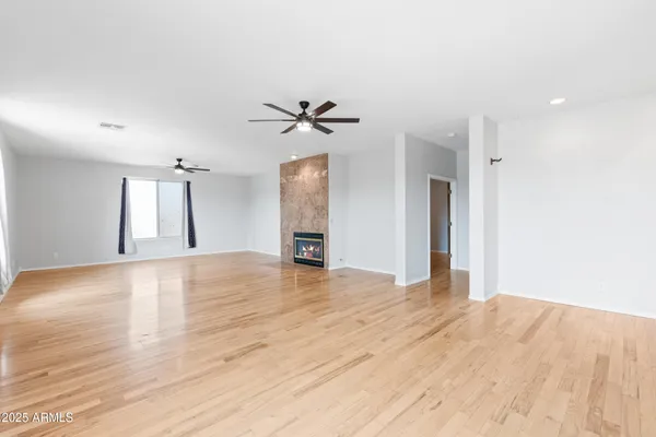 a view of empty room with wooden floor and fan