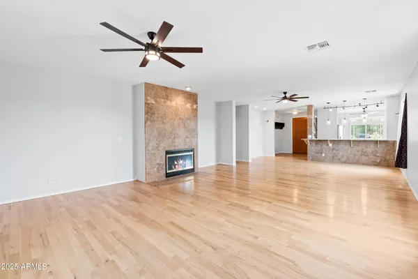 a view of empty room with wooden floor and ceiling fan