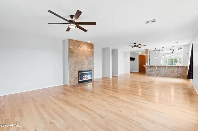 a view of empty room with wooden floor and ceiling fan