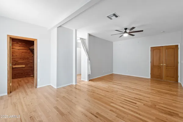 a view of empty room with wooden floor and fan