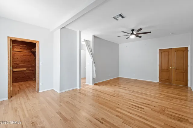 a view of empty room with wooden floor and fan