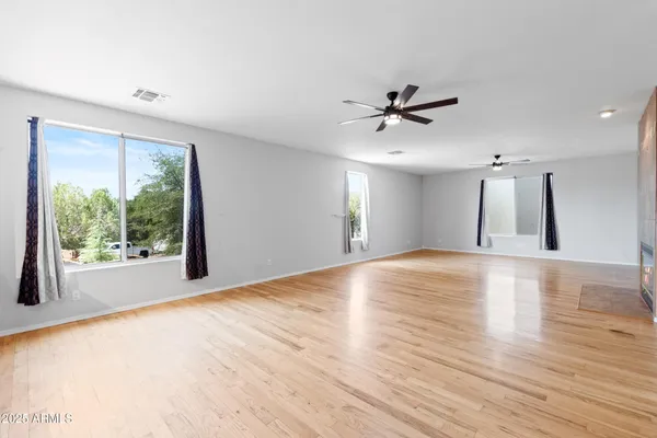 a view of an empty room with window and wooden floor