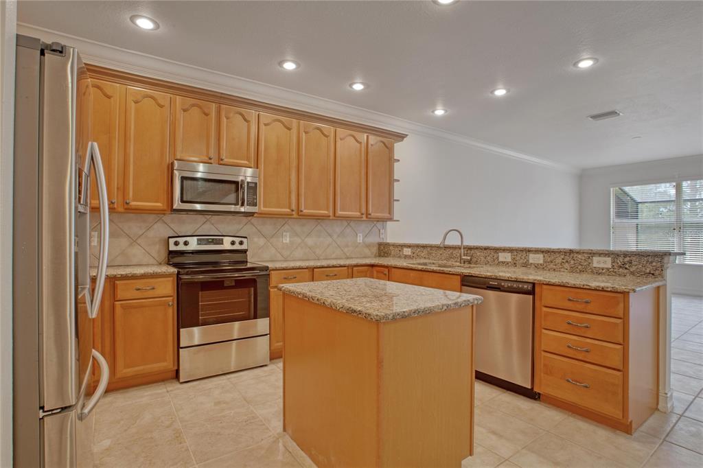 1344 Ribolla Drive Palm Harbor, FL 34683 - Photo 4 of 26 a kitchen with kitchen island granite countertop a sink stove and refrigerator