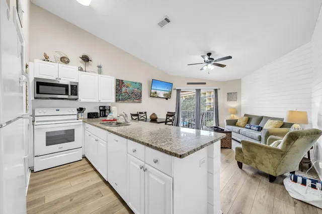 a kitchen with stainless steel appliances granite countertop a table chairs and a refrigerator