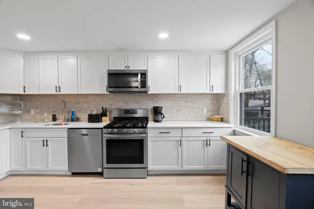 a kitchen with stainless steel appliances granite countertop a stove a sink and a microwave