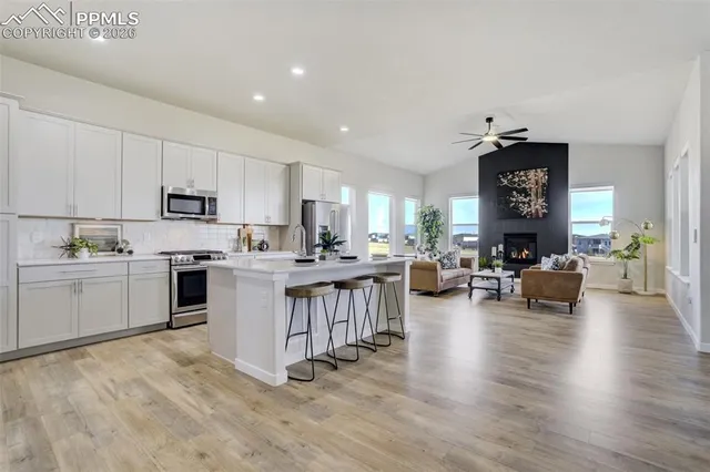 a kitchen with a sink dishwasher a stove and white cabinets with wooden floor