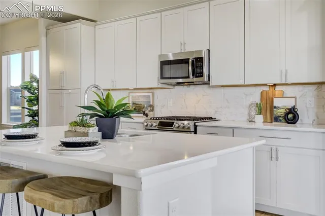 a kitchen with stainless steel appliances a microwave a sink a stove and white cabinets