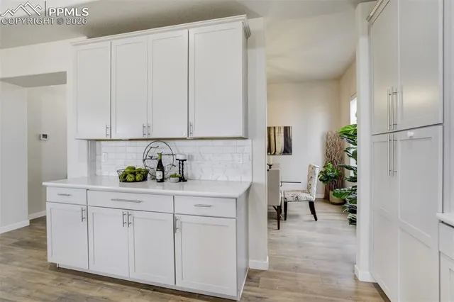 a kitchen with white cabinets and wooden floor