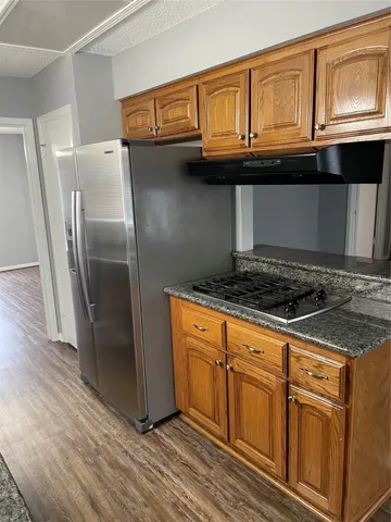 a kitchen with granite countertop a stove a sink and a refrigerator