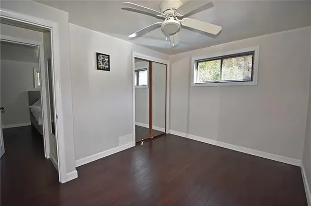 an empty room with wooden floor fan and windows