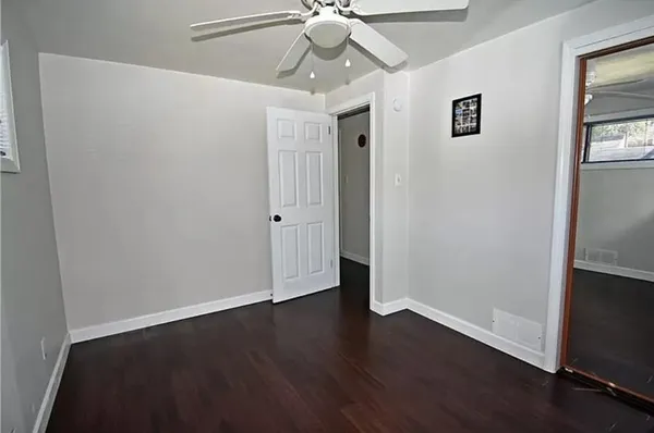 a view of an empty room with wooden floor and a ceiling fan
