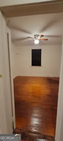 a view of an empty room with wooden floor and a fireplace