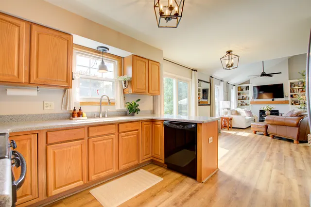 a large kitchen with stainless steel appliances granite countertop a stove a sink dishwasher and a microwave with wooden floor