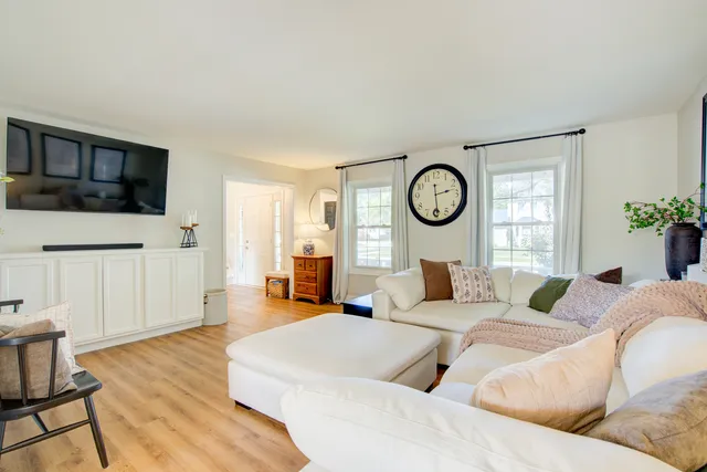 a living room with furniture a large window and wooden floor