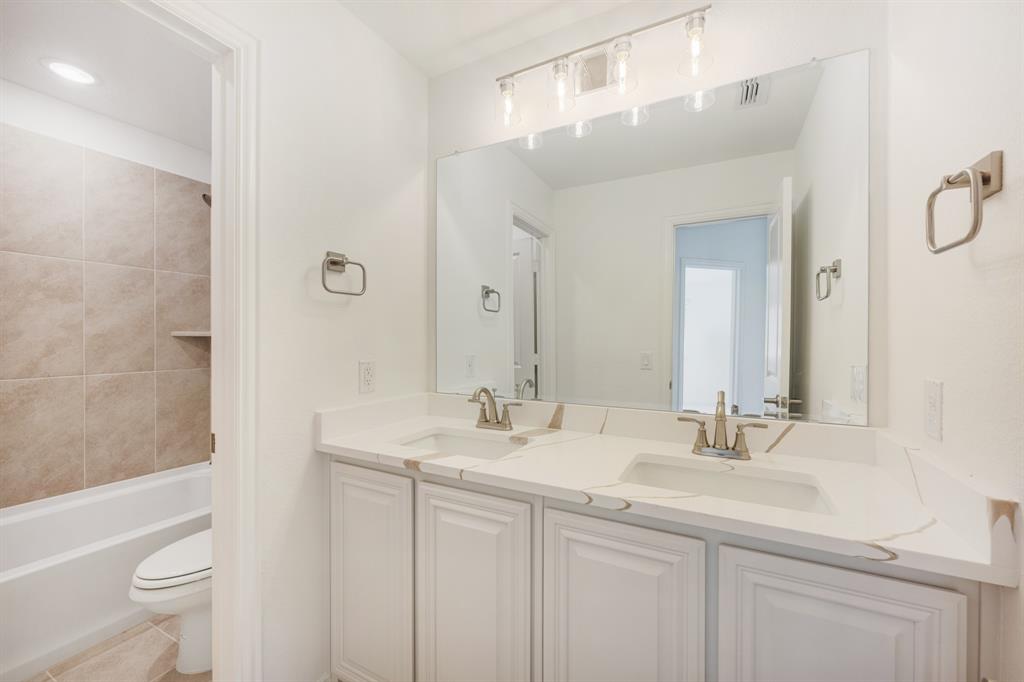 7308 Iris Road Aubrey, TX 76227 - Photo 33 of 40 a bathroom with a double vanity sink toilet and shower
