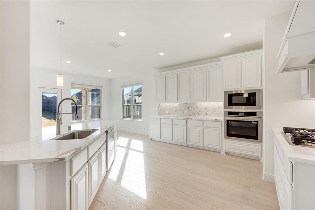 7308 Iris Road Aubrey, TX 76227 - Photo 8 of 40 a kitchen with stainless steel appliances kitchen island granite countertop a stove and a sink