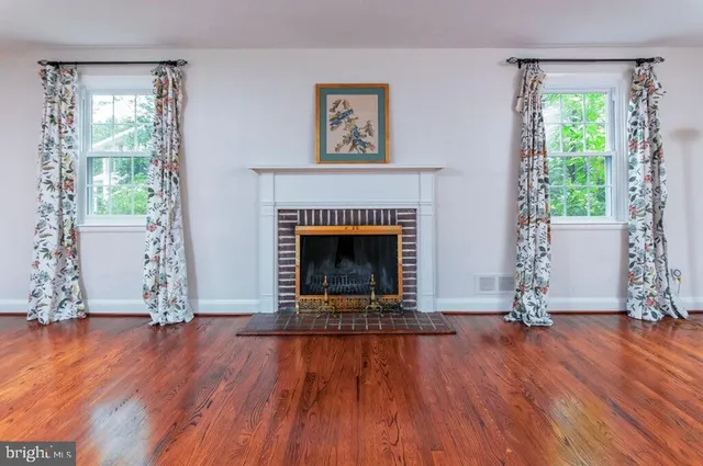 an empty room with wooden floor a fireplace and windows