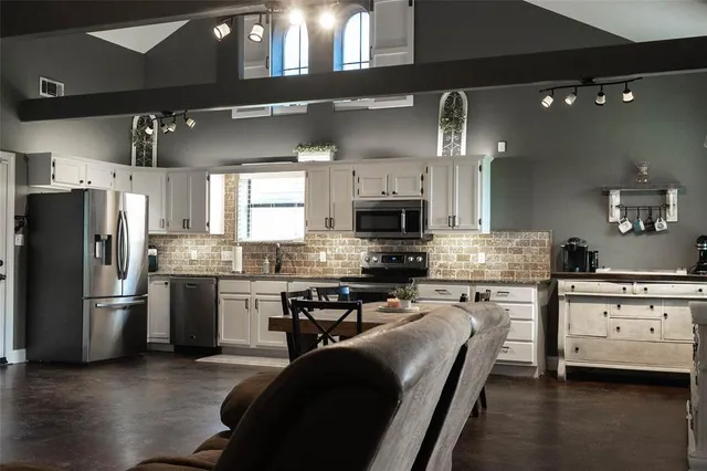 a kitchen with stainless steel appliances a stove a sink dishwasher a refrigerator and a oven with wooden floor