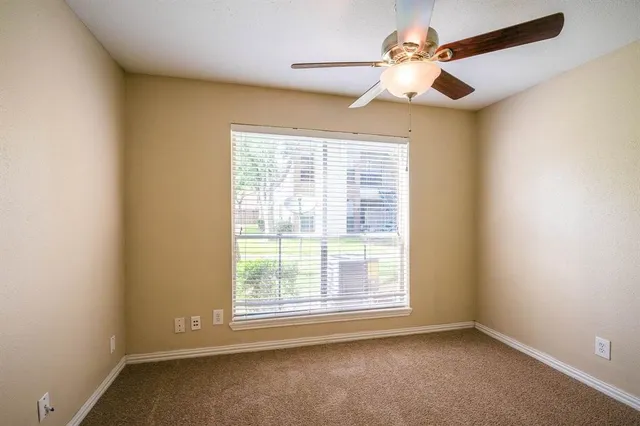 an empty room with a window and a fan