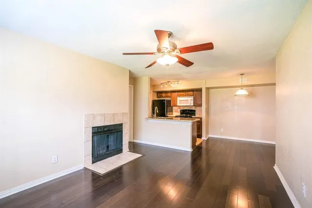 a view of a livingroom with a fireplace a ceiling fan and wooden floor