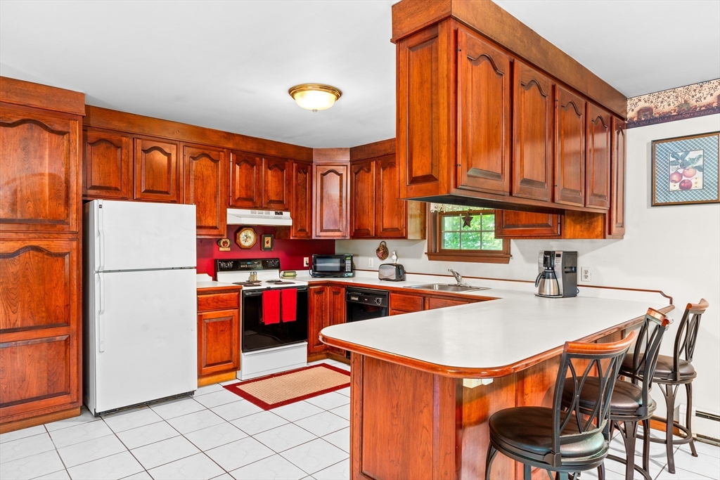 465 Doe Valley Road Athol, MA 01331 - Photo 3 of 36 a kitchen with a refrigerator a stove a sink dishwasher and a dining table with wooden cabinet