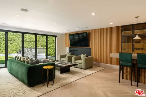 a living room with furniture a flat screen tv and floor to ceiling window
