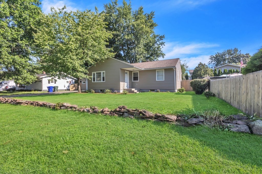 a view of a house with a big yard with plants and large trees