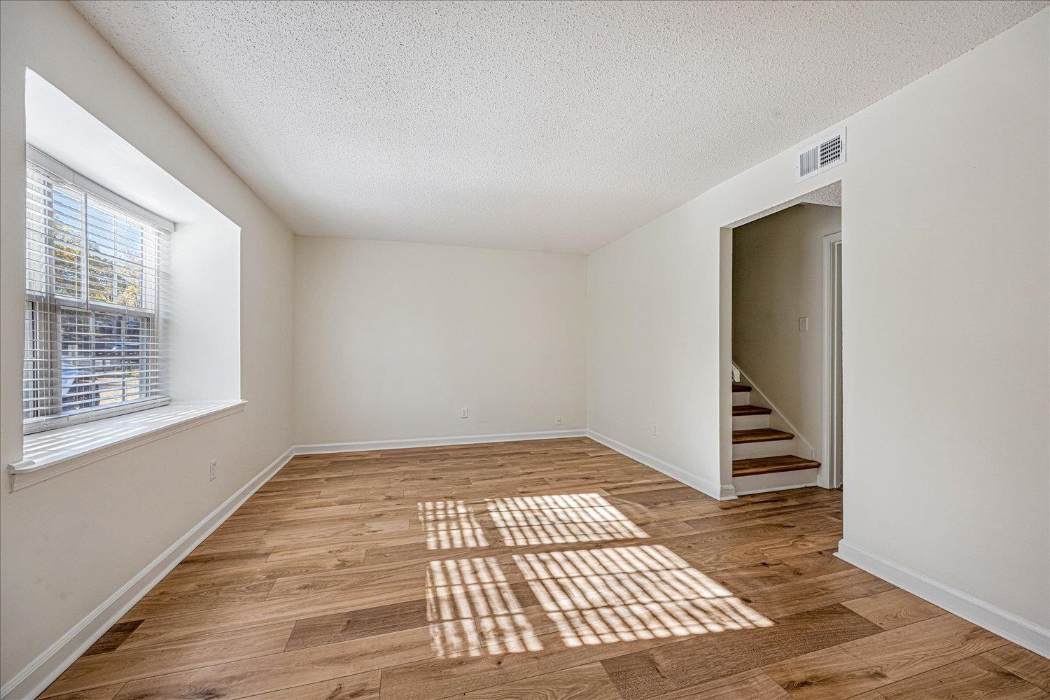 6452 Macon Road Memphis, TN 38134 - Photo 4 of 22 Spare room featuring stairs, light wood-style floors, and a textured ceiling