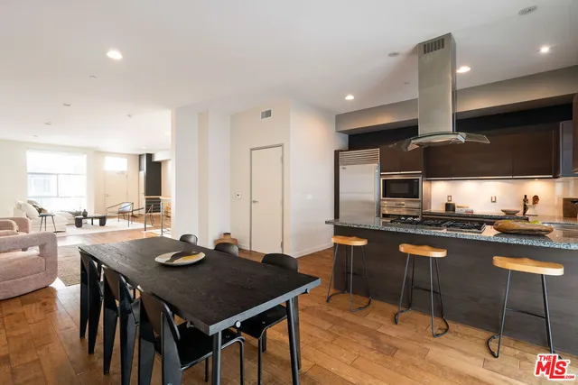 a kitchen with stainless steel appliances granite countertop a stove a refrigerator a kitchen island and chairs