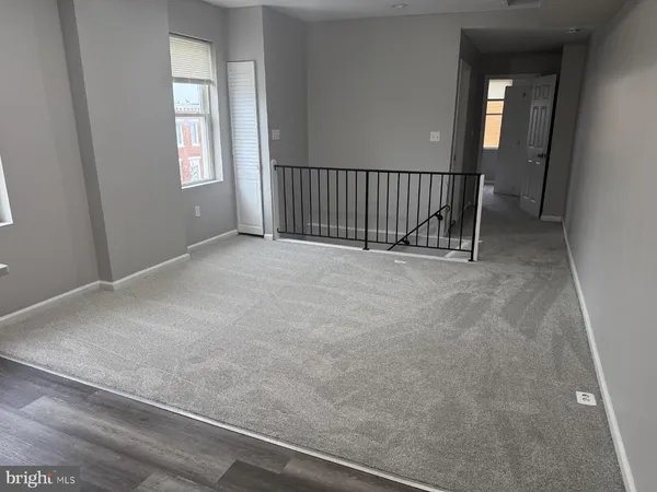 a view of an empty room with wooden floor and windows