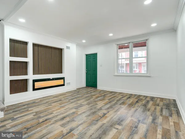 a view of an empty room with wooden floor and windows